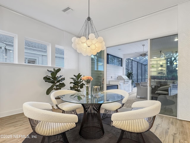 dining space with crown molding, a chandelier, and light hardwood / wood-style flooring