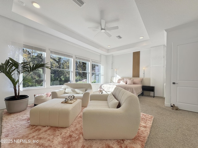 carpeted bedroom with a raised ceiling and ceiling fan