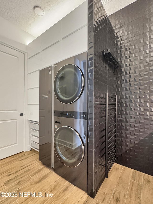 laundry area with stacked washer / drying machine and a textured ceiling