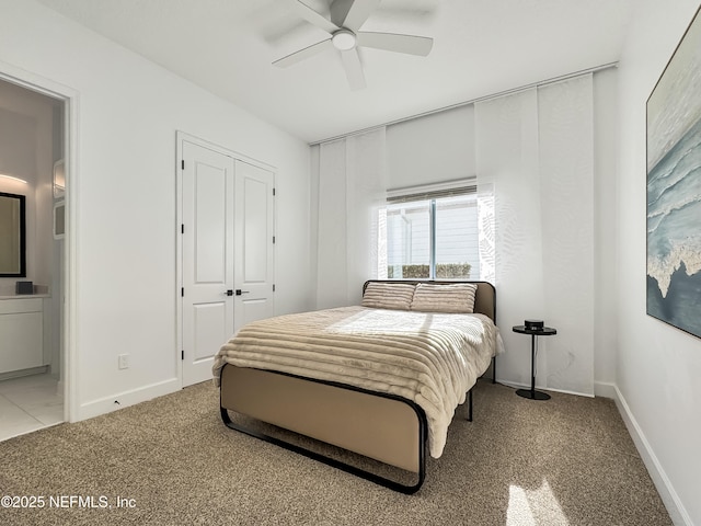 bedroom with ensuite bathroom, light colored carpet, ceiling fan, and a closet