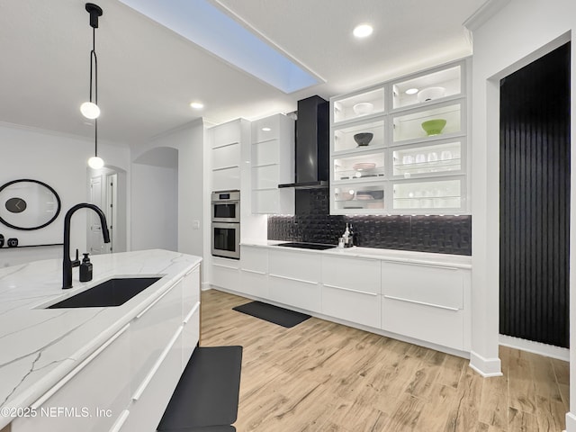 kitchen featuring white cabinetry, sink, hanging light fixtures, and wall chimney exhaust hood