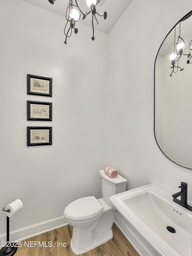 bathroom with hardwood / wood-style flooring, sink, a chandelier, and toilet