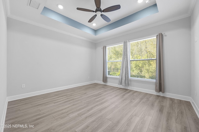 unfurnished room featuring crown molding, a tray ceiling, light hardwood / wood-style flooring, and ceiling fan