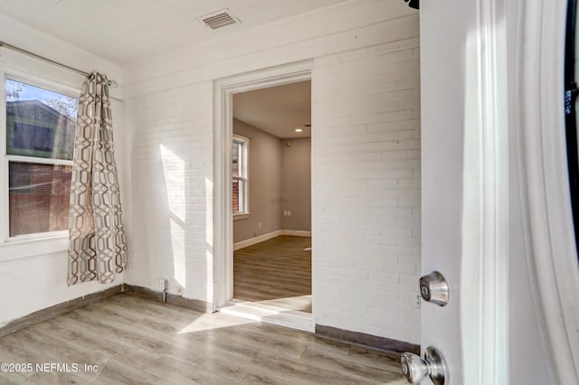 empty room featuring wood-type flooring and brick wall