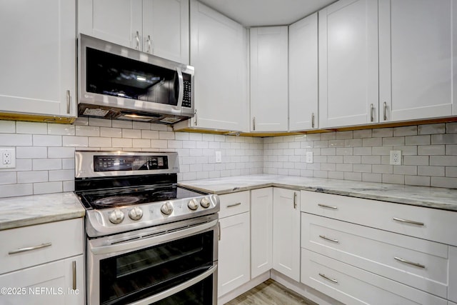 kitchen featuring light stone counters, stainless steel appliances, decorative backsplash, and white cabinets