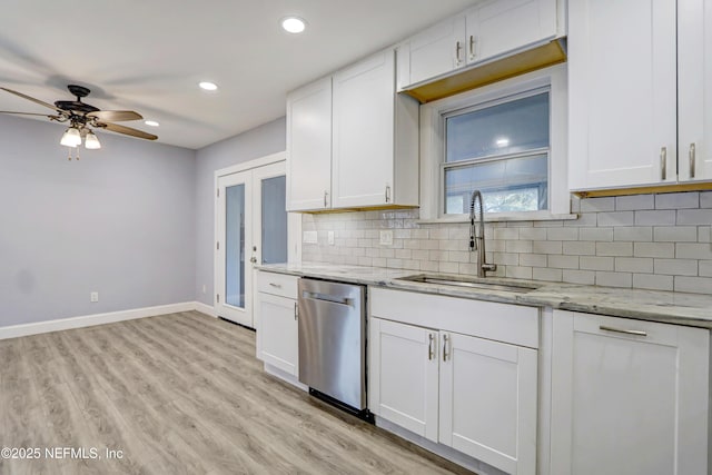 kitchen with tasteful backsplash, sink, white cabinets, stainless steel dishwasher, and light stone counters