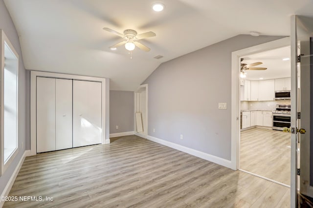 unfurnished bedroom with ceiling fan, lofted ceiling, light hardwood / wood-style floors, and a closet