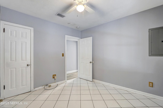 empty room featuring light tile patterned floors, electric panel, and ceiling fan