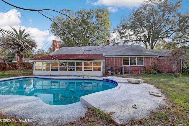 view of swimming pool featuring a patio area, a sunroom, and a diving board