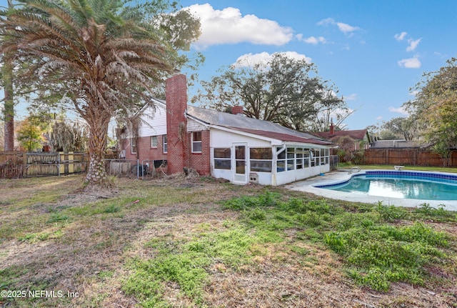 back of house featuring a fenced in pool and a sunroom