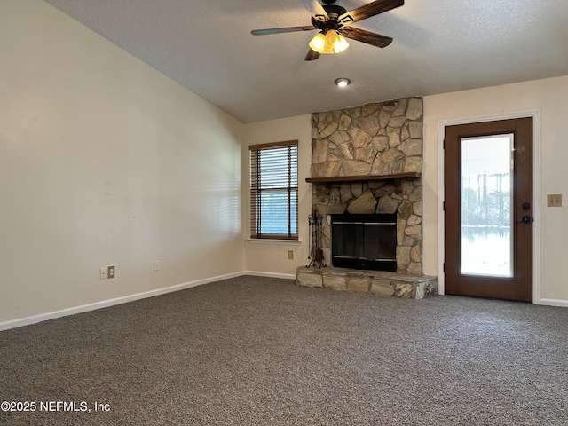 unfurnished living room featuring a stone fireplace, vaulted ceiling, plenty of natural light, and carpet