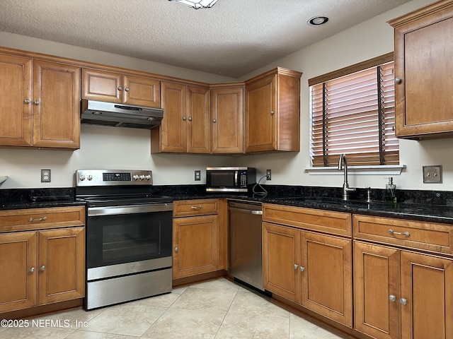 kitchen featuring appliances with stainless steel finishes, a textured ceiling, and dark stone countertops