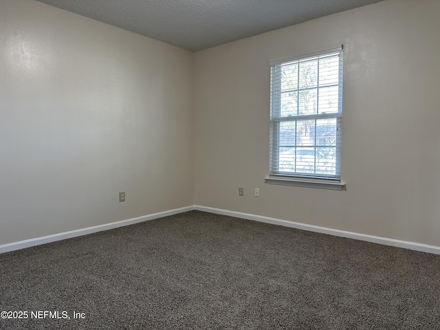 unfurnished room with dark colored carpet and a textured ceiling