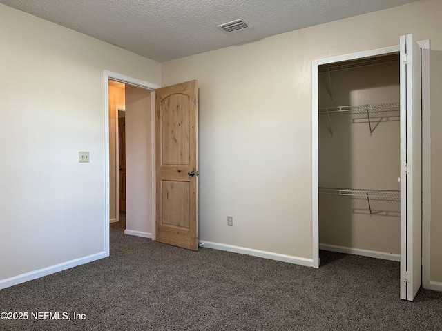 unfurnished bedroom with dark carpet, a closet, and a textured ceiling