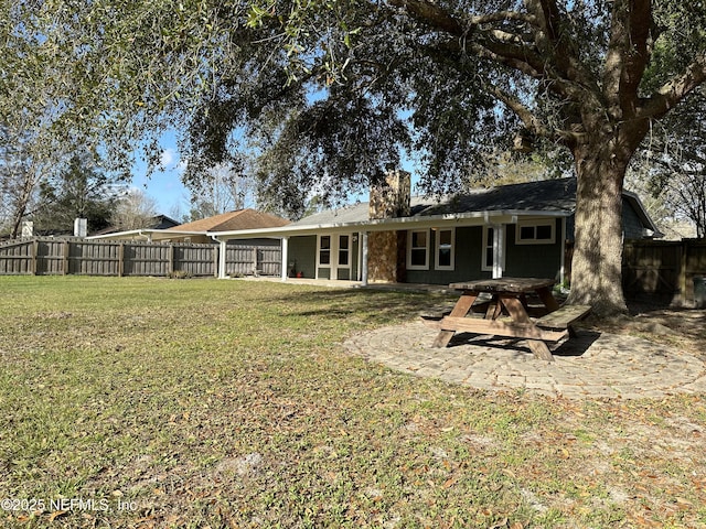 rear view of house featuring a lawn and a patio