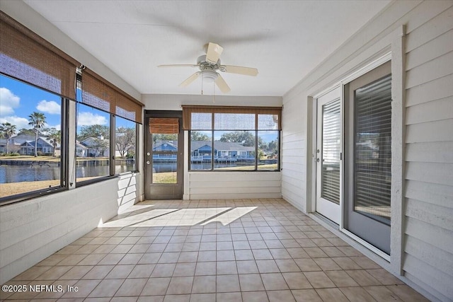 unfurnished sunroom featuring ceiling fan and a water view