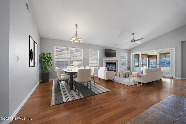 dining area with dark hardwood / wood-style flooring, ceiling fan with notable chandelier, and lofted ceiling