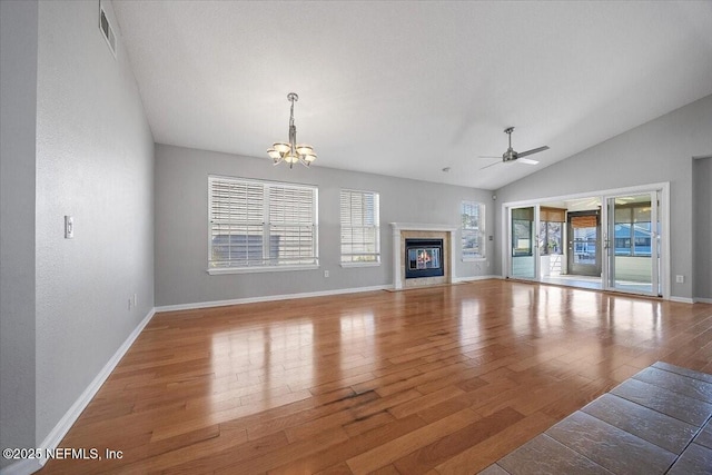 living room featuring ceiling fan with notable chandelier, lofted ceiling, a premium fireplace, and hardwood / wood-style floors