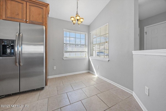 kitchen featuring stainless steel refrigerator with ice dispenser, light tile patterned flooring, decorative light fixtures, a chandelier, and vaulted ceiling