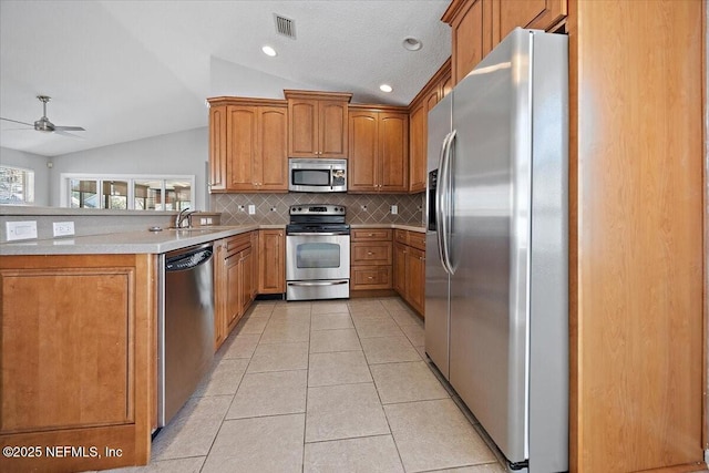 kitchen with vaulted ceiling, stainless steel appliances, sink, and light tile patterned floors