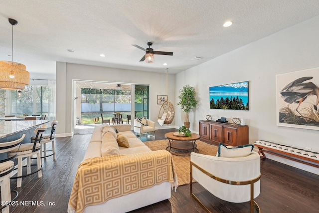 living room with ceiling fan, dark hardwood / wood-style flooring, and a textured ceiling