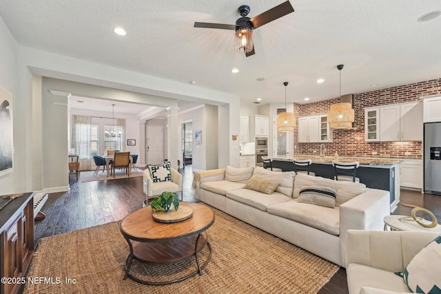 living room featuring dark hardwood / wood-style flooring, ceiling fan, a textured ceiling, and brick wall