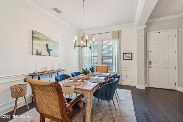 dining space with dark wood-type flooring, crown molding, and a chandelier