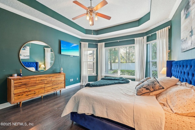 bedroom featuring crown molding, a textured ceiling, dark hardwood / wood-style floors, a raised ceiling, and ceiling fan