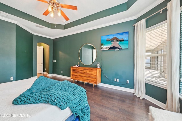 bedroom with dark wood-type flooring, ornamental molding, a tray ceiling, and multiple windows