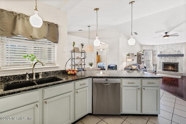 kitchen with light tile patterned flooring, sink, hanging light fixtures, stainless steel dishwasher, and a high end fireplace