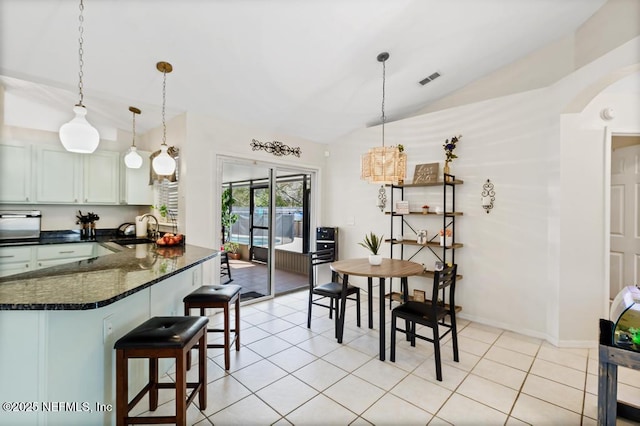 dining room with lofted ceiling, sink, and light tile patterned floors