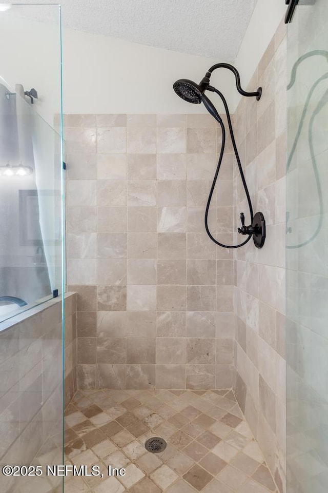 bathroom featuring a tile shower and a textured ceiling