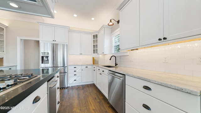 kitchen with sink, white cabinetry, appliances with stainless steel finishes, light stone countertops, and decorative backsplash