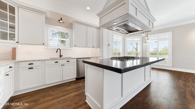 kitchen with appliances with stainless steel finishes, sink, custom exhaust hood, hanging light fixtures, and light stone counters