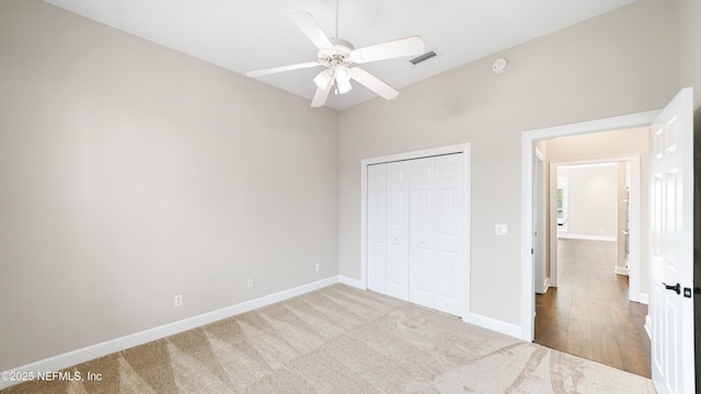 unfurnished bedroom featuring ceiling fan, light colored carpet, and a closet