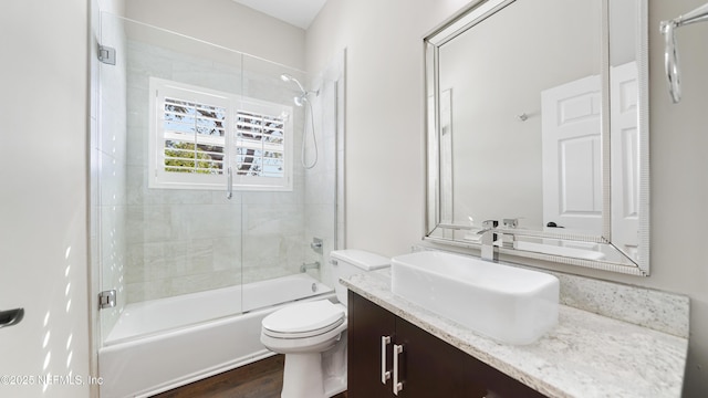 full bathroom with vanity, combined bath / shower with glass door, wood-type flooring, and toilet