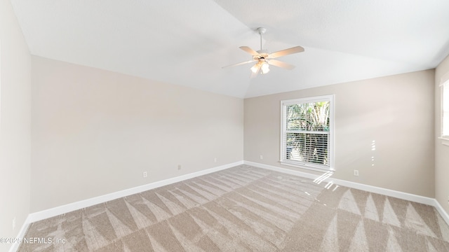 empty room featuring vaulted ceiling, light carpet, and ceiling fan