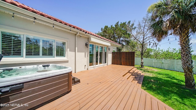 deck with a hot tub and a lawn