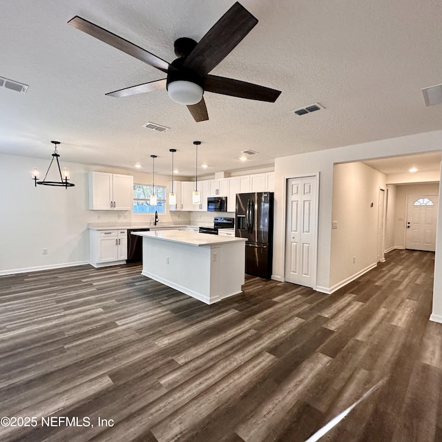 kitchen featuring a kitchen island, dark hardwood / wood-style floors, decorative light fixtures, white cabinets, and black appliances