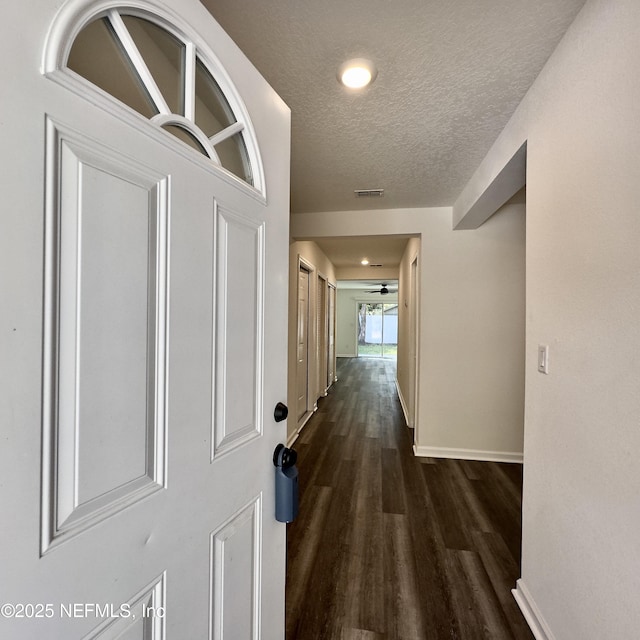 hall with dark wood-type flooring and a textured ceiling