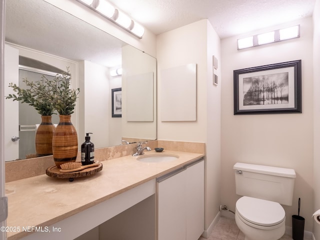 bathroom with vanity, toilet, and a textured ceiling