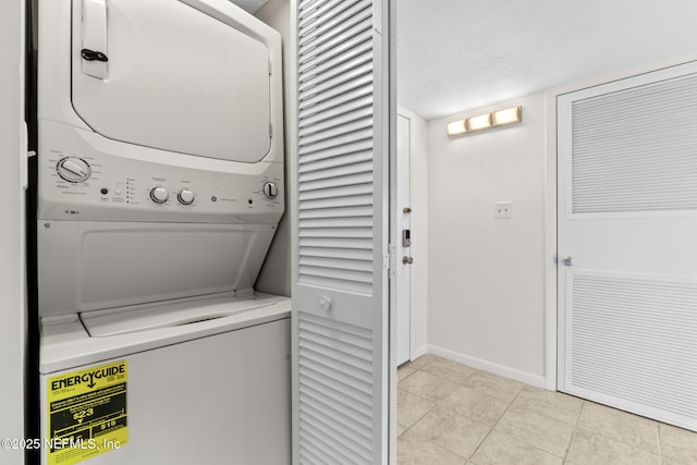 6000 San Jose Blvd Unit 6F, Jacksonville, FL 32217 - laundry area featuring baseboards, a textured ceiling, light tile patterned flooring, stacked washer and dryer, and laundry area
