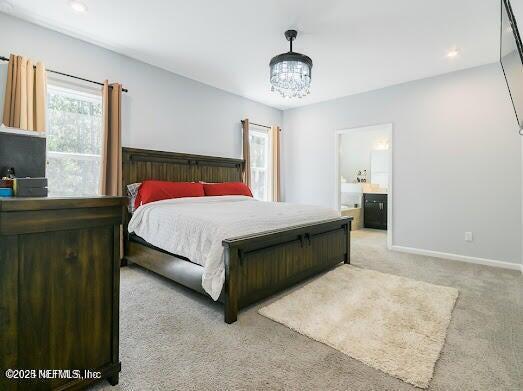 bedroom with light colored carpet and ensuite bath