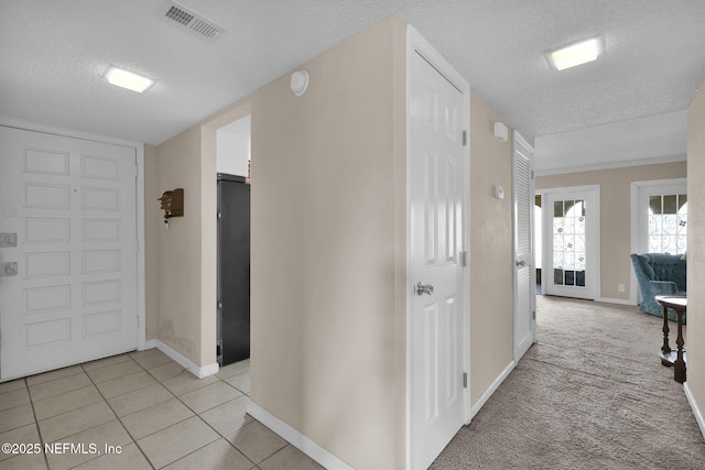 corridor with light tile patterned floors and a textured ceiling