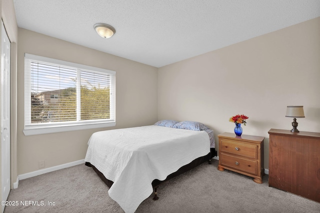 bedroom featuring carpet floors, baseboards, and a textured ceiling