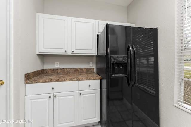 kitchen featuring black fridge with ice dispenser and white cabinets