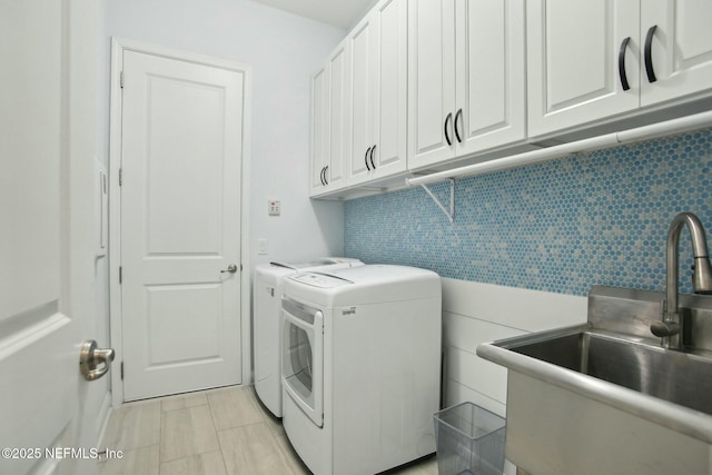 clothes washing area featuring washer and dryer, sink, light tile patterned floors, and cabinets