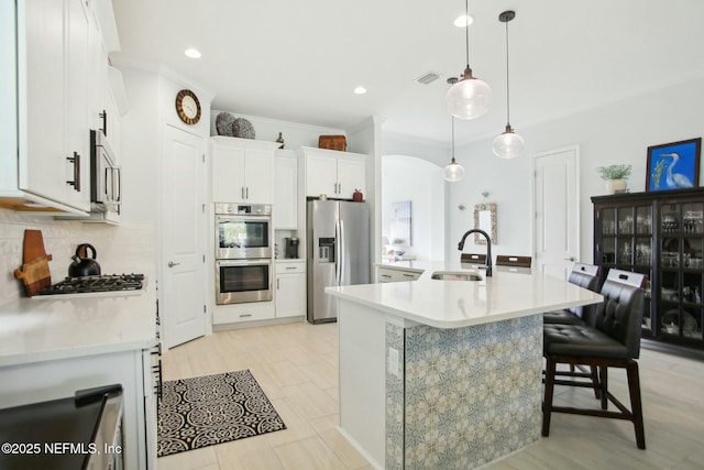 kitchen featuring sink, appliances with stainless steel finishes, decorative backsplash, white cabinets, and decorative light fixtures