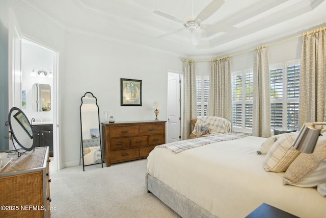 bedroom featuring ensuite bathroom, crown molding, light colored carpet, a raised ceiling, and ceiling fan