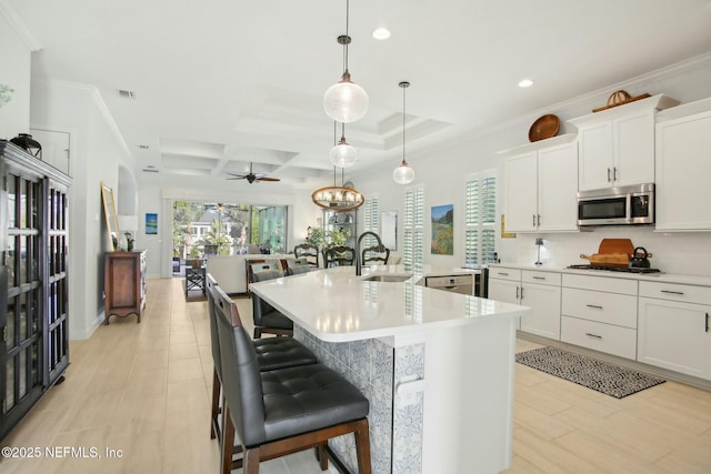 kitchen with pendant lighting, sink, white cabinetry, an island with sink, and a kitchen bar